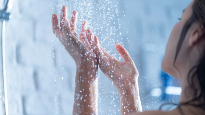 femme sous la douche qui mouille ses mains