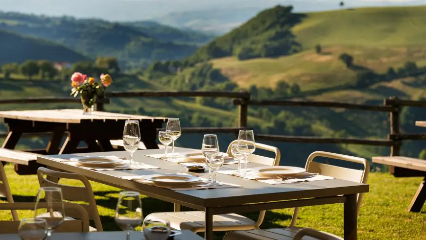 table d'un restaurant local donnant sur les collines, avec des verres et des fleurs