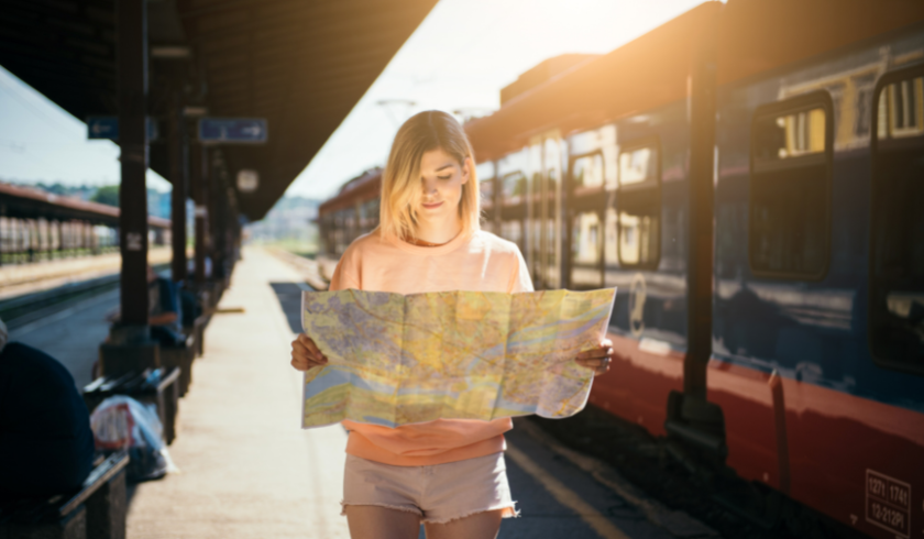 femme qui veut voyager vert lit une carte sur le quai d'une gare